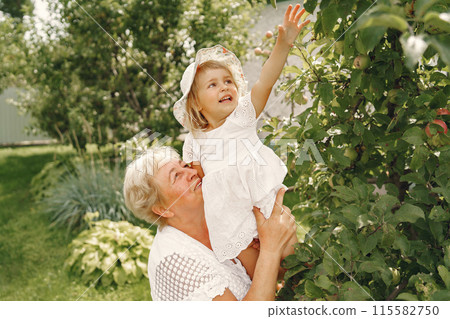 Grandmother and granddaughter together, hugging and joyfully laughing in a Flowering apricot garden in April. Family outdoors lifestyle. 115582750