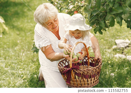 Grandmother and granddaughter together, hugging and joyfully laughing in a Flowering apricot garden in April. Family outdoors lifestyle. 115582755