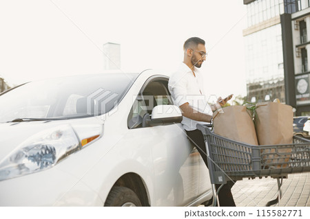 Arab man use smart phone while waiting for charging the battery in car. Eco awarness. 115582771