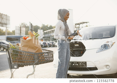 Islam black girl charging electro car. Eco car. Islam black girl charging electro car. Eco car. 115582778