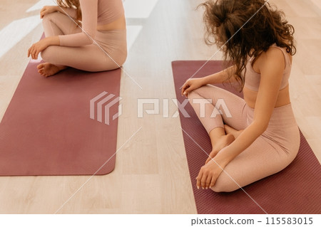 Well looking middle aged sporty woman, fitness instructor in pink sportswear doing stretching and pilates on yoga mat in the studio with mirror. Female fitness yoga. Healthy lifestyle and harmony. Well looking middle aged sporty woman, fitness instructor in pink sportswear doing stretching and pilates on yoga mat in the studio with mirror. Female fitness yoga. Healthy lifestyle and harmony. 115583015