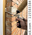 Window installation. The process of insulating windows with construction foam. A builder's hand seals the cracks between the building and the window frame. Construction and insulation of the building. 115583384