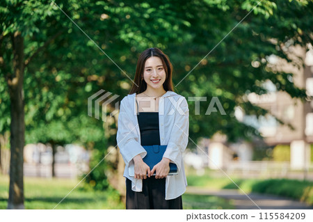 A young woman walking with a notebook A young woman walking with a notebook 115584209