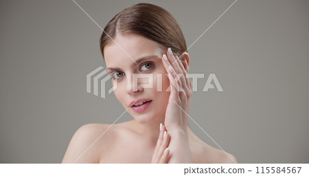 Beauty, health, cosmetics, anti-aging therapy and skin care concept - young beautiful brunette Caucasian woman posing and looking at the camera with a calm confident look like in a mirror Beauty, health, cosmetics, anti-aging therapy and skin care concept - young beautiful brunette Caucasian woman posing and looking at the camera with a calm confident look like in a mirror 115584567