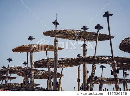 A wooden umbrellas set against the backdrop of a clear blue sky A wooden umbrellas set against the backdrop of a clear blue sky 115586156