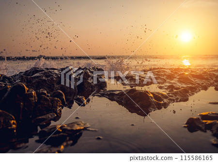 A large rocks surrounded by waves of the ocean A large rocks surrounded by waves of the ocean 115586165