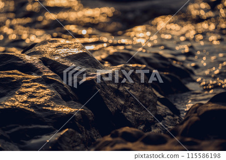 A large rocks surrounded by waves of the ocean A large rocks surrounded by waves of the ocean 115586198