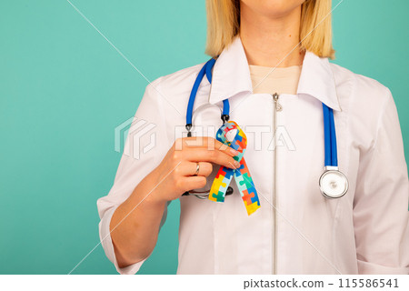 World Autism awareness and pride day with Puzzle pattern ribbon. The doctor's hand World Autism awareness and pride day with Puzzle pattern ribbon. The doctor's hand 115586541