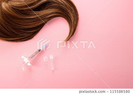 Hair treatment concept. Medical syringe and hair isolated on a white background Hair treatment concept. Medical syringe and hair isolated on a white background 115586580