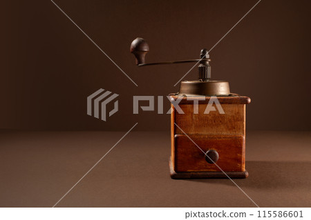 Vintage coffee grinder on brown background 115586601