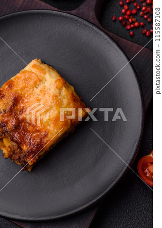 Delicious baked lasagna pasta with meat, sauce, salt, spices and herbs on a dark concrete background 115587108