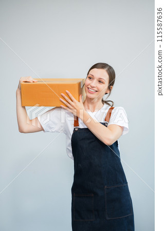 woman holding parcels box and looking to camera, isolated on white background. 115587636