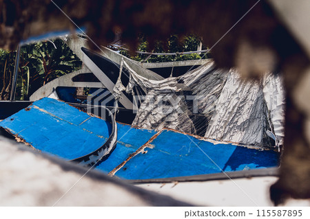 Old and rusty motor boats on a landfill surrounded by tropical forest 115587895