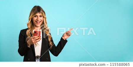 Excited transgender businesswoman holding smartphone while gesturing towards blank space Excited transgender businesswoman holding smartphone while gesturing towards blank space 115588065