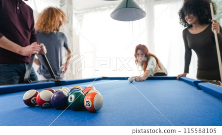Male and female friends playing pool together in game room at home Male and female friends playing pool together in game room at home 115588105