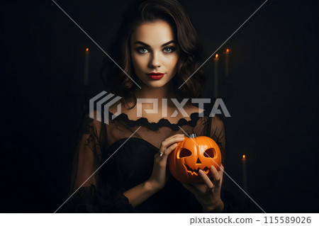In a dark room, a mysterious woman in black holds a Halloween pumpkin under candlelight 115589026