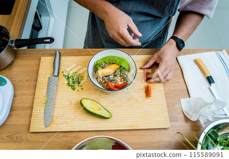 Chef at the kitchen preparing healthy quinoa bowl with avocado 115589091