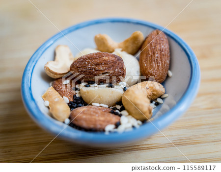 A bowl filled with assorted nuts and seeds is placed on a rustic wooden table A bowl filled with assorted nuts and seeds is placed on a rustic wooden table 115589117
