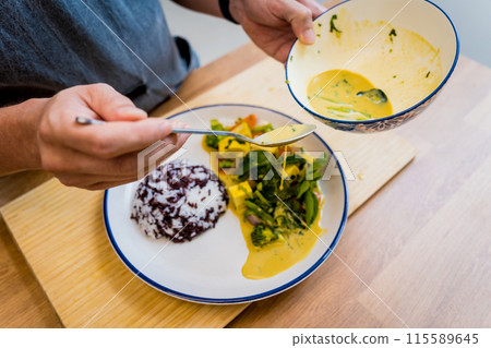 Chef at the kitchen preparing green curry with herbs and rice Chef at the kitchen preparing green curry with herbs and rice 115589645