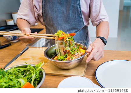 Chef at the kitchen preparing spicy glass noodle salad Chef at the kitchen preparing spicy glass noodle salad 115591488