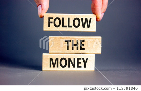 Follow the money symbol. Concept words Follow the money on beautiful wooden blocks. Beautiful grey table grey background. Businessman hand. Business and follow the money concept. Copy space. 115591840