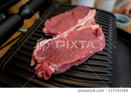 Raw fillet beef meat for steaks on the home electric grill Raw fillet beef meat for steaks on the home electric grill 115593169