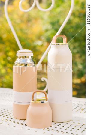 Modern stainless steel and plastic thermos with cup on park in autumn. vacuum thermos. Concept for outdoor activities, hot drink, hike, travel. 115593188