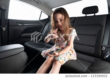 Kid with smartphone on rear car seat Kid with smartphone on rear car seat 115594932