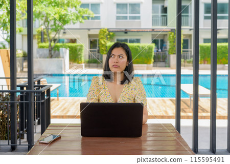 Confused woman using laptop computer and wearing yellow floral dress outdoors Confused woman using laptop computer and wearing yellow floral dress outdoors 115595491