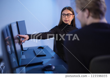 Cybersecurity professionals discussing and analyzing network security data on multiple screens in office 115596035