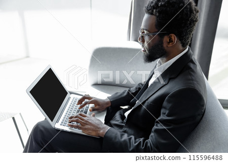Businessman using laptop for work while sitting on chair in office Businessman using laptop for work while sitting on chair in office 115596488