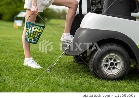 Unrecognizable woman golfer posing by the golf cart on the green 115596502