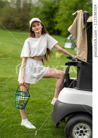 Joyful golfer posing near her car with golf equipment on the course 115596504