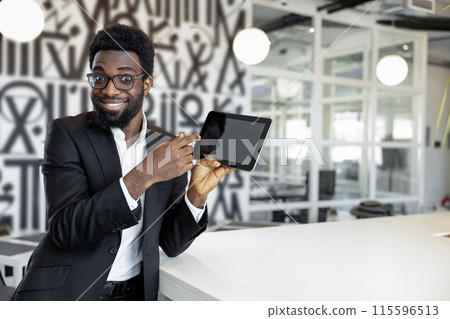 Smiling african american businessman in elegant suit with a gadget in hands 115596513
