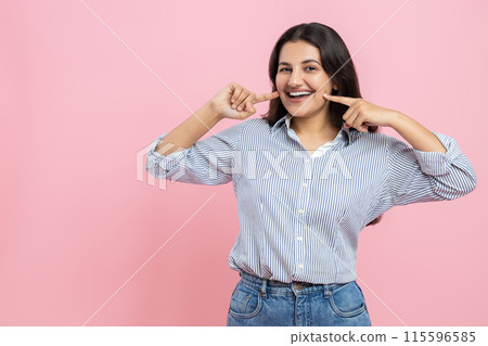 Cheerful smiling Indian woman pointing at her perfect smile 115596585
