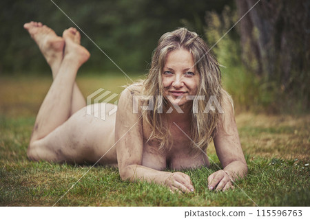 Naked beautiful dirty woman lies in the evening forest Naked beautiful dirty woman lies in the evening forest 115596763