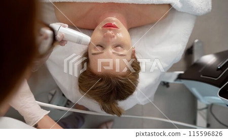 Therapist cosmetologist makes a rejuvenating facial massage for a woman in a spa salon. Beauty and body concept. The process of skin rejuvenation in a cosmetology office. Lymphatic drainage massage Therapist cosmetologist makes a rejuvenating facial massage for a woman in a spa salon. Beauty and body concept. The process of skin rejuvenation in a cosmetology office. Lymphatic drainage massage 115596826