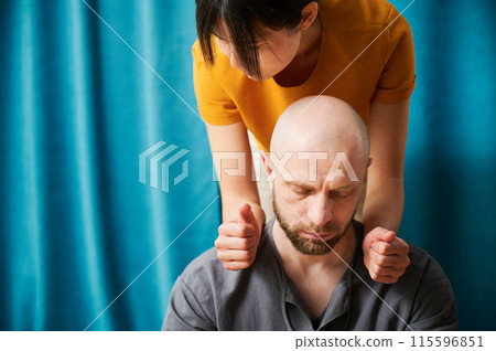 Masseuse making thai yoga massage. Woman therapist doing traditional massage treatment for male patient indoors. Close up view of bald client meditating, enjoying hand massage in calm atmosphere. 115596851