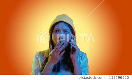 Shocking call. Bad news. Blue color neon light astonished woman use phone talk surprised overwhelmed expression isolated on orange gradient empty space background. Shocking call. Bad news. Blue color neon light astonished woman use phone talk surprised overwhelmed expression isolated on orange gradient empty space background. 115596960