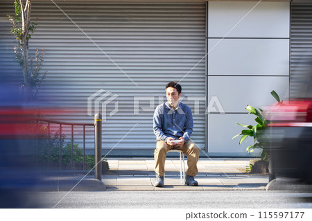 A man sitting on the street conducting a traffic survey 115597177