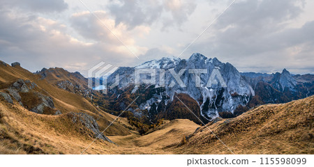 Autumn Dolomites mountain scene from hiking path betwen Pordoi Pass and Fedaia Lake, Italy. Snowy Marmolada Glacier and Fedaia Lake in far. 115598099