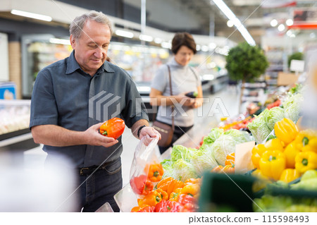 Elderly man chooses pepper in vegetable and fruit department Elderly man chooses pepper in vegetable and fruit department 115598493