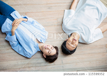 A friendly couple lying on the floor A friendly couple lying on the floor 115599352