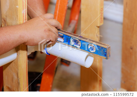 With help of level, sanitary pipes are leveled during gluing 115599572
