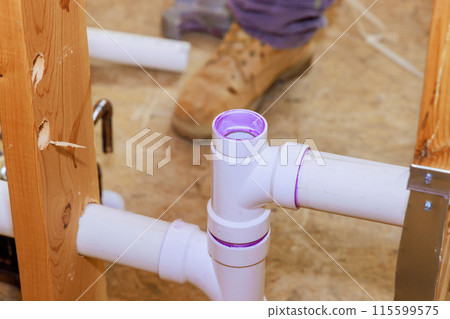 Technician plumber using glue is applied to plastic PVC pipes 115599575