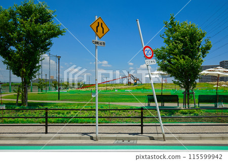 Road sign and long slide in front of the lawn square at Miyamae Park 115599942