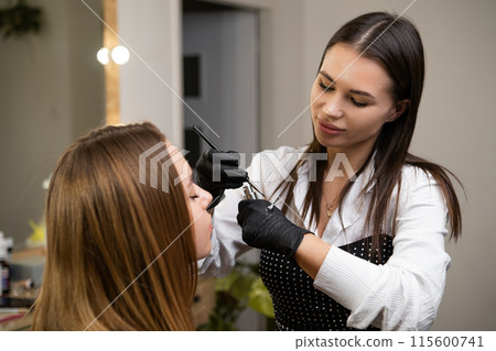 A woman receives a brow lamination treatment at a beauty salon A woman receives a brow lamination treatment at a beauty salon 115600741