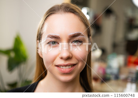Portrait of a young woman during the procedure of lamination of the brow. Portrait of a young woman during the procedure of lamination of the brow. 115600748