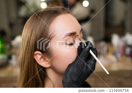 Close up beauty master doing a conturing for brow dying for young lady.  115600756