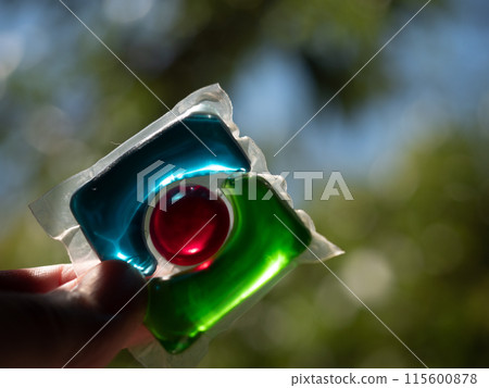 Laundry detergent pod. Men hand holds colorful water soluble sachet. Packs or liquitabs are water-soluble pouches containing highly concentrated laundry detergent, softener and other laundry products Laundry detergent pod. Men hand holds colorful water soluble sachet. Packs or liquitabs are water-soluble pouches containing highly concentrated laundry detergent, softener and other laundry products 115600878